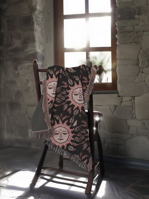 Luxurious woven cotton throw featuring dreamy blush pink sun faces with closed eyes against black background with delicate ray patterns and elegant fringe trim. Perfect celestial wall hanging, witchy bedroom decor, or dark academia throw blanket.